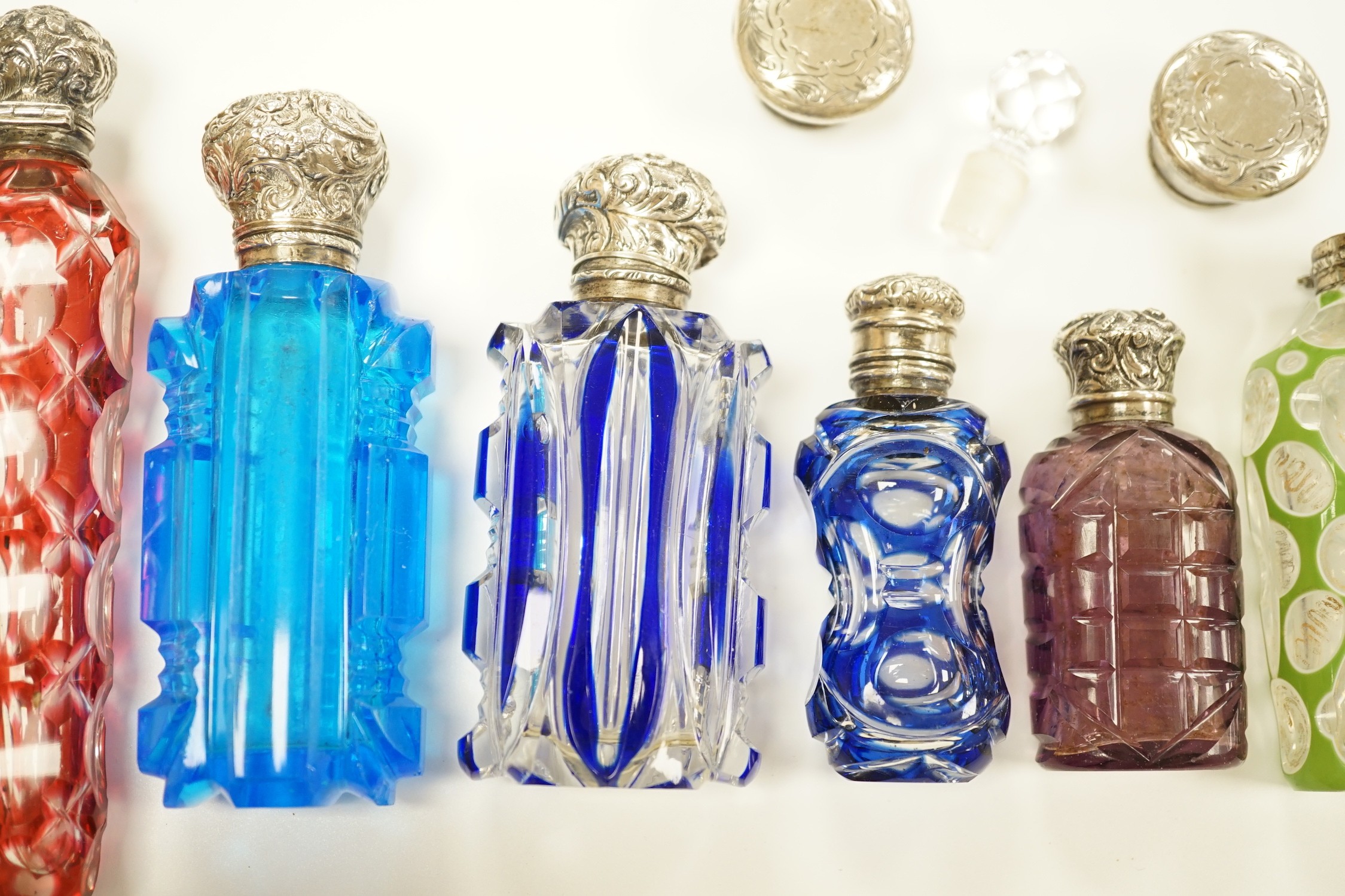 A late Victorian silver mounted cut glass scent bottle, Charles Boyton II, London, 1896, 82mm and six other late 19th/early 20th century, silver or white metal mounted coloured cut glass scent bottles (some a.f.) and two